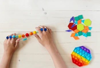 Hands exploring beads and colorful shapes during a tabletop activity